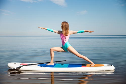 A young woman doing yoga on a paddleboard in the water